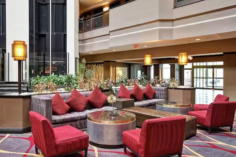 Elegant hotel lobby with high ceilings, red accent chairs, and warm ambient lighting