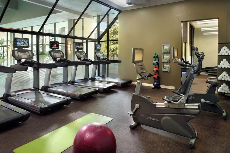 Modern hotel fitness center with treadmills, exercise bikes, mirrored walls, and exercise ball