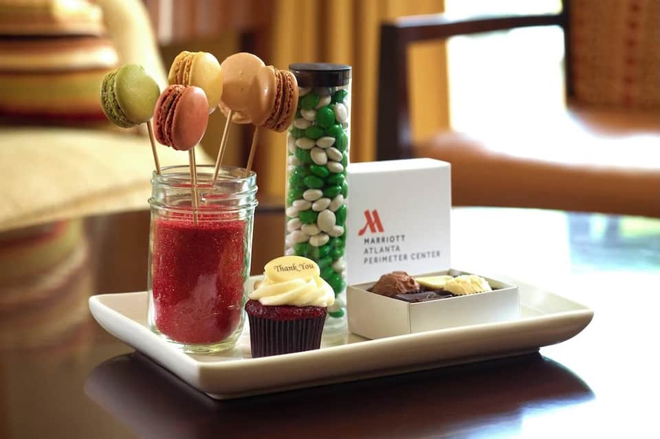 Welcome amenities tray with macarons, cupcake, candy jar, and Marriott branding