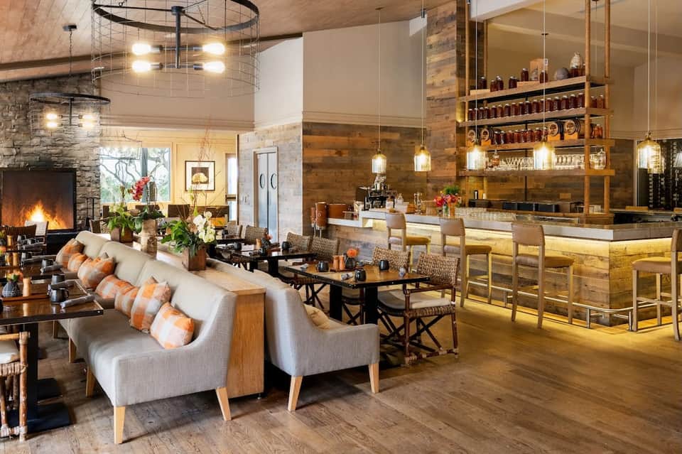 Modern resort lobby with fireplace, wooden bar, high ceilings, pendant lighting, and contemporary furnishings