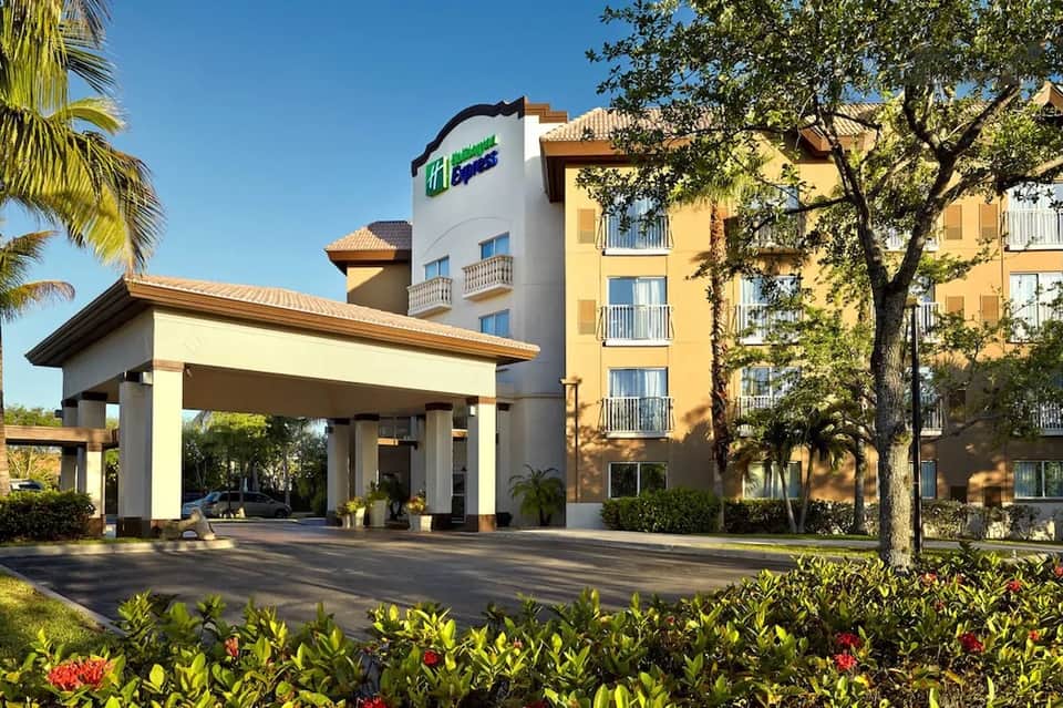 Holiday Inn hotel exterior with yellow building, covered entrance, and landscaped grounds