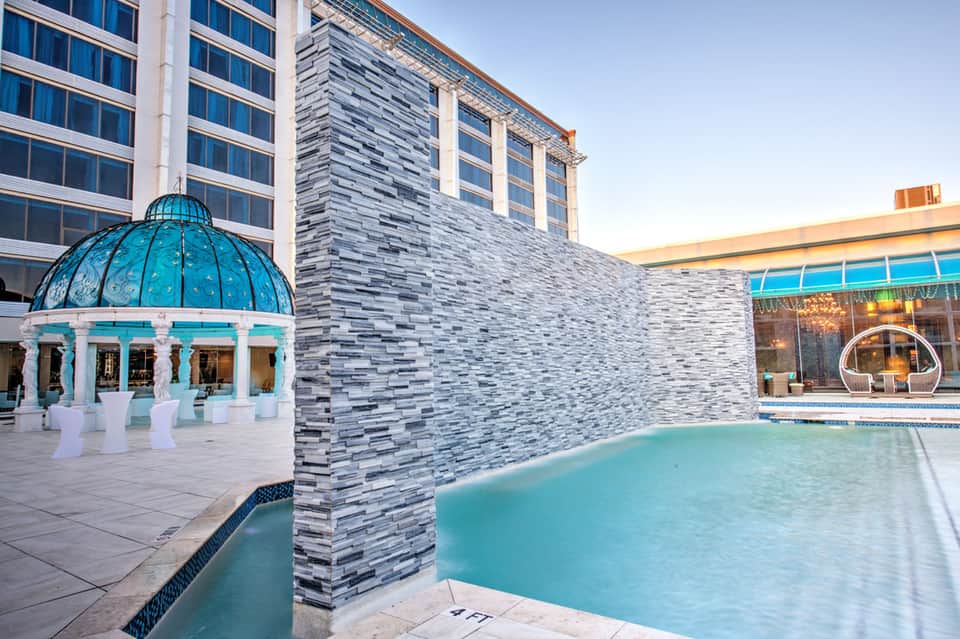 Modern hotel spa area with turquoise indoor pool, glass dome gazebo, and contemporary stone architecture