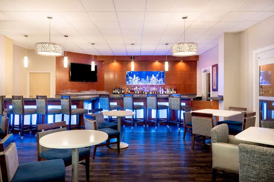 Hotel lounge bar with modern lighting, blue seating, and wood accents
