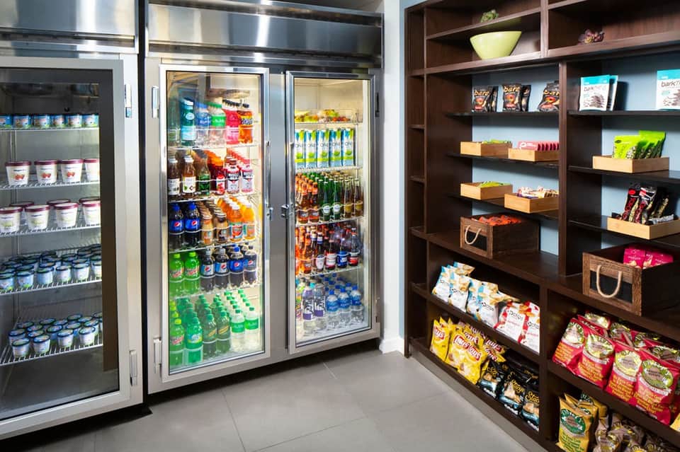 Hotel snack bar with refrigerated beverage cases and shelved convenience items for guests