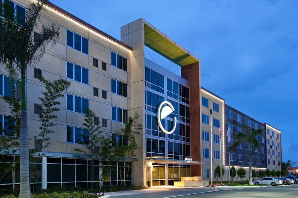 Modern hotel exterior with contemporary architecture, illuminated entrance, and landscaping at dusk