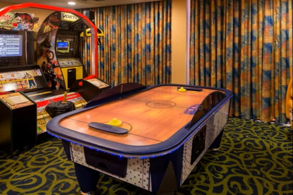 Game room with air hockey table, arcade machine, and decorative curtains