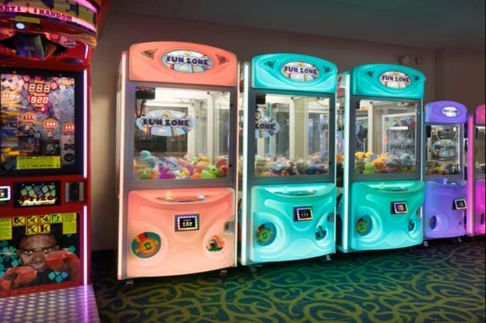 Arcade game room with illuminated claw machines and gaming cabinets