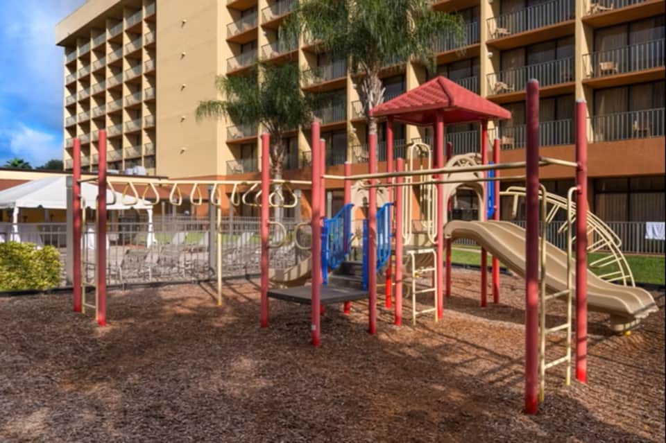 Red playground structure with slides and climbing equipment for children
