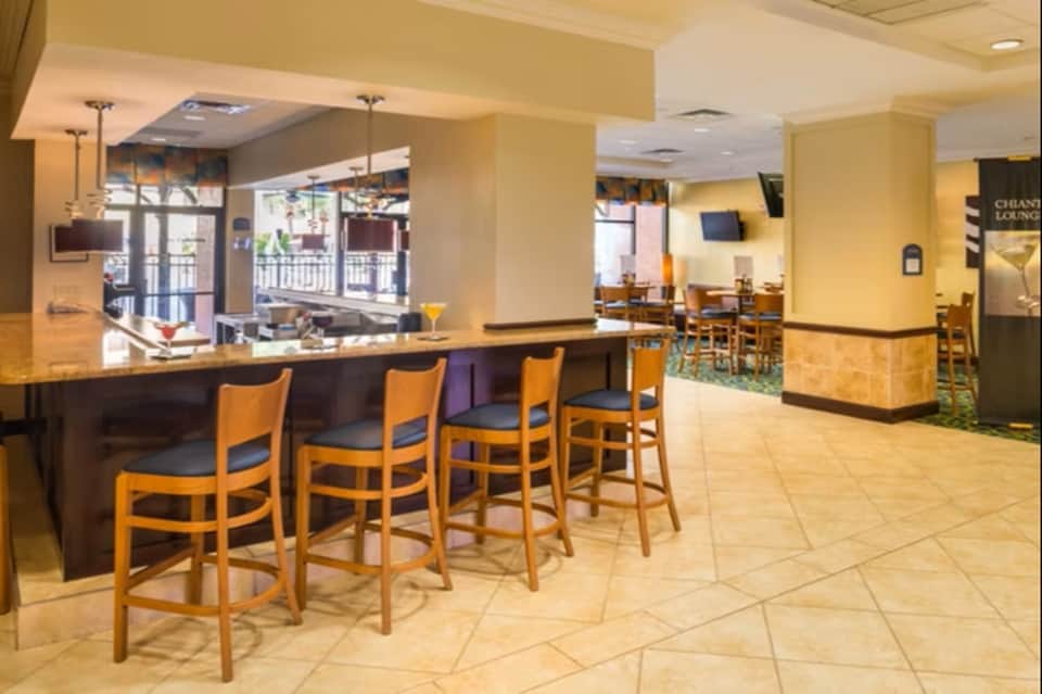Hotel bar and lounge with wooden bar counter, yellow walls, and seating areas