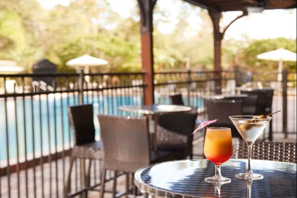 Poolside lounge seating with cocktails, lounge chairs, and umbrellas overlooking resort pool