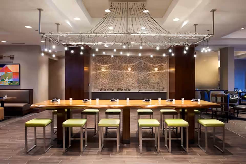 Modern conference room with long wooden table, lime green stools, and decorative ceiling