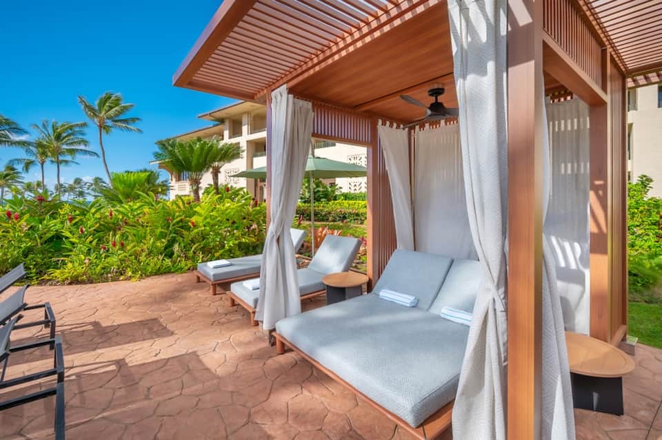 Luxury cabana beds with white curtains on terrace overlooking tropical gardens and ocean