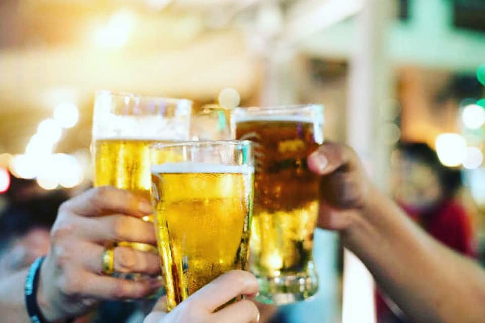 Three glasses of golden beer toasting at a bar or restaurant event