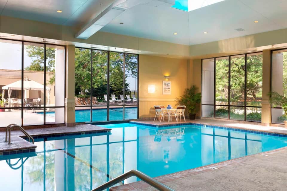 Indoor heated pool with large windows overlooking outdoor pool area