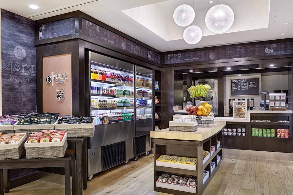 Hotel market cafe with refrigerated displays, fresh produce, and pendant lights