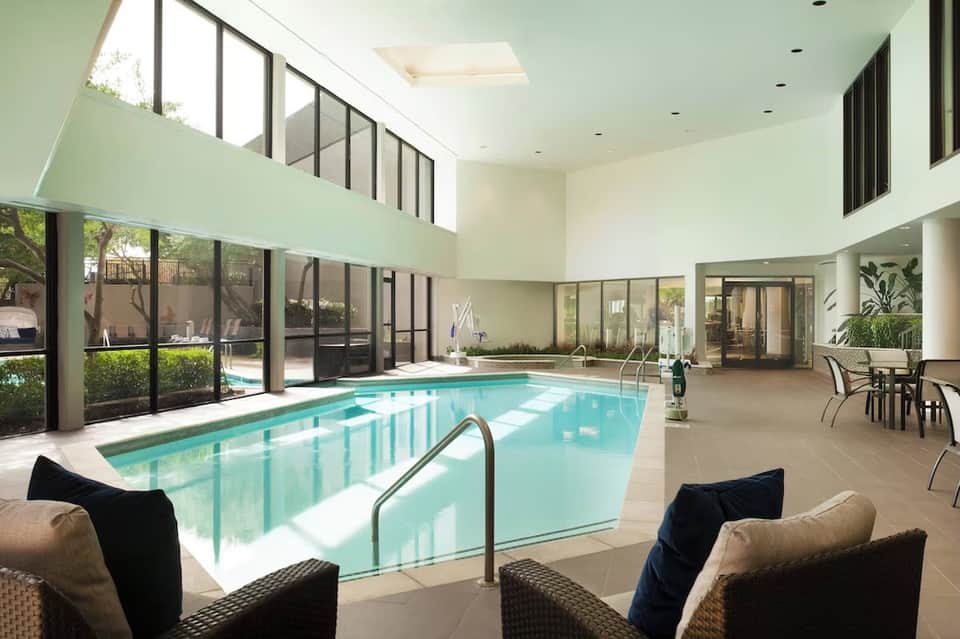 Indoor heated pool facility with high ceilings, natural light, and modern comfortable seating
