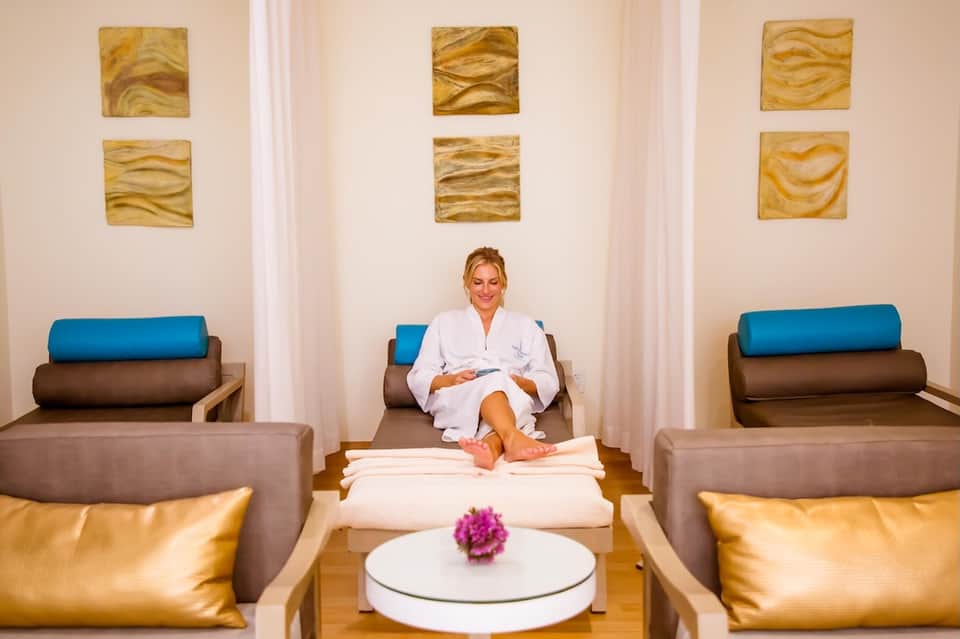Spa relaxation room with woman in white robe, modern seating, and gold wall art