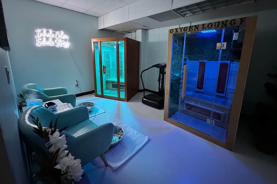 Modern wellness spa with neon sign, sauna cabins with blue lighting, lounge chairs, and oxygen lounge