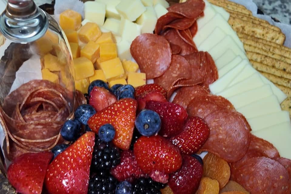 Gourmet charcuterie and appetizer board with cured meats, cheeses, berries, and crackers