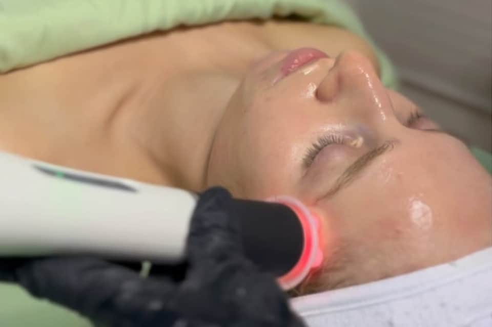 Spa facial treatment with laser technology device on relaxed client's face