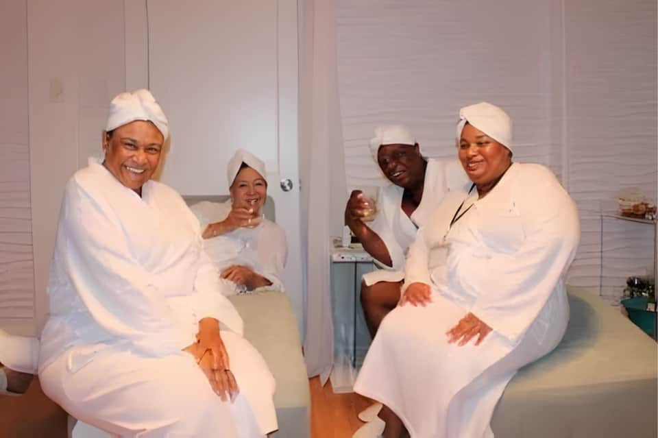 Group of people in spa robes and headwraps sitting together in relaxation room