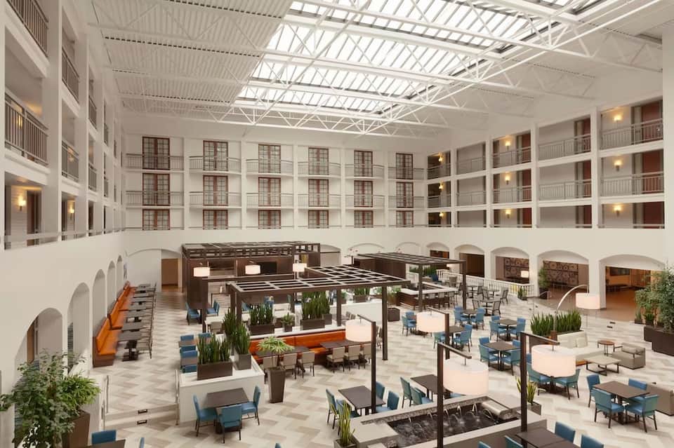 Modern hotel atrium lobby with white railings, skylights, and contemporary seating areas