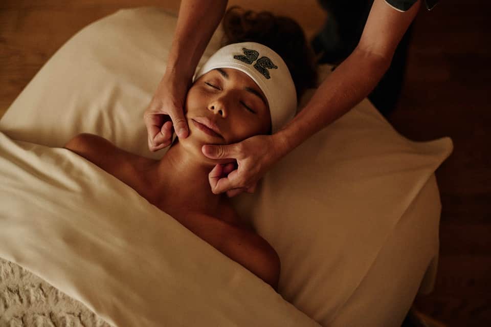 Woman receiving facial massage treatment at spa with hands working on her face