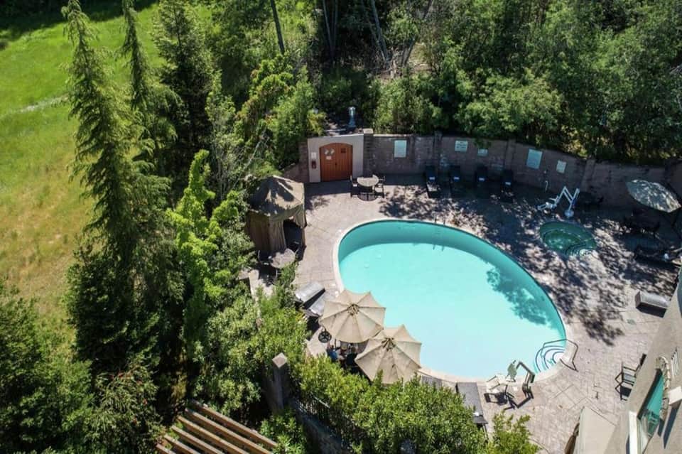 Aerial view of resort pool surrounded by tall cypress trees and stone privacy walls