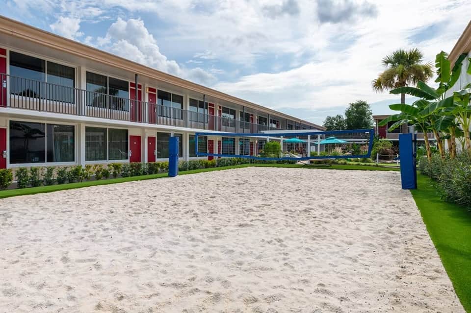 Contemporary beachfront resort building with red and blue doors, sandy courtyard, and manicured landscaping