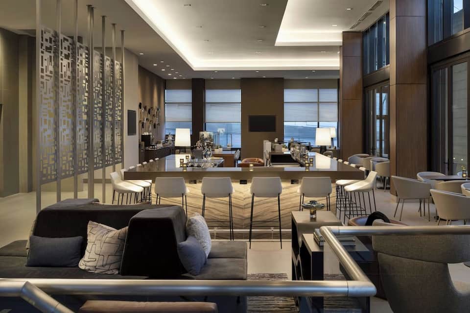 Modern resort lounge with ocean view, geometric wall art, bar counter, and contemporary furnishings