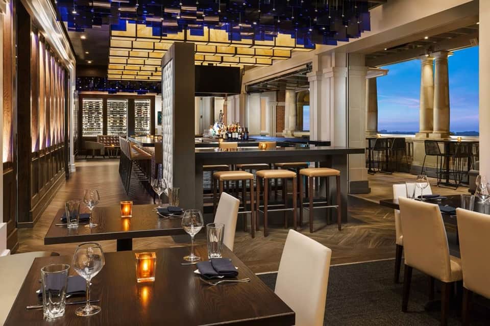 Upscale restaurant with bar, exposed brick, modern lighting, and panoramic window views