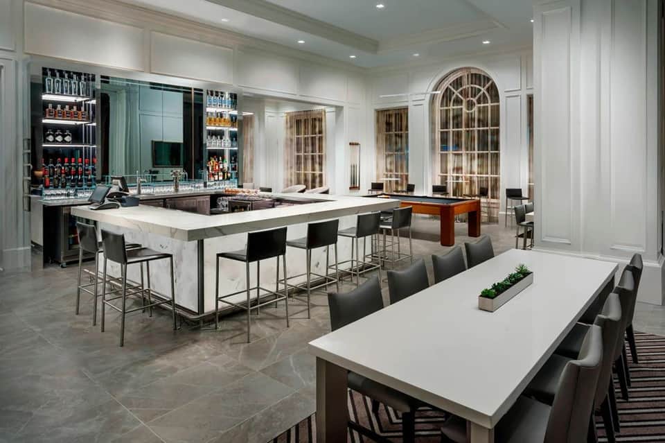 Upscale hotel bar with marble countertops, elegant seating, and fully stocked shelving