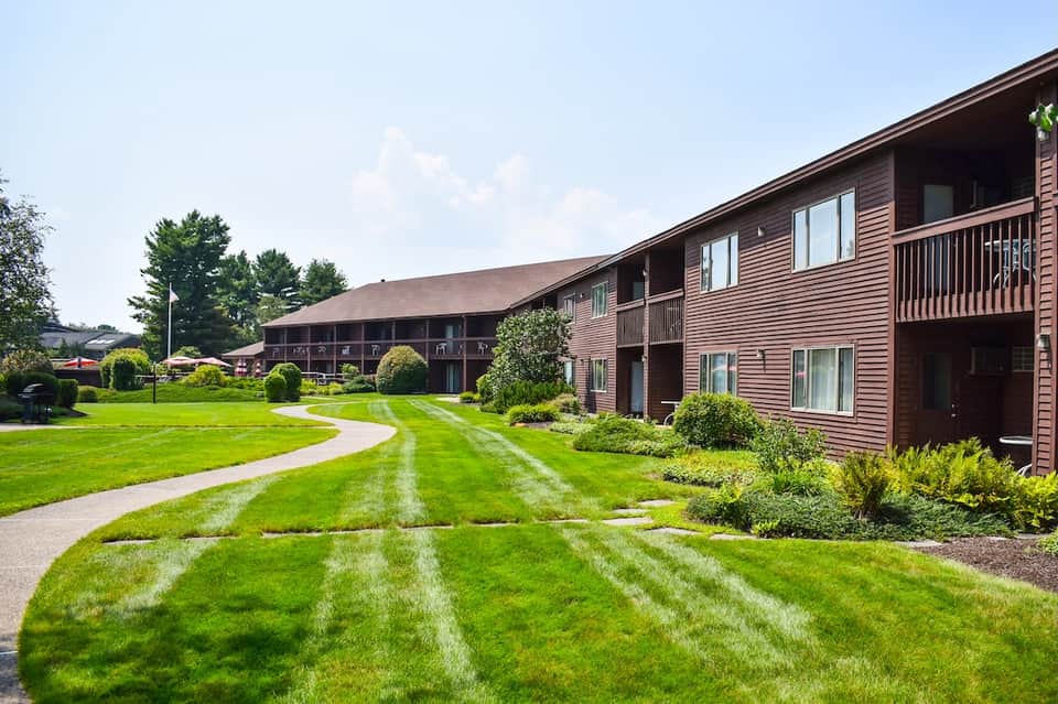 Resort exterior showing brown wooden buildings with manicured lawns and landscaped grounds