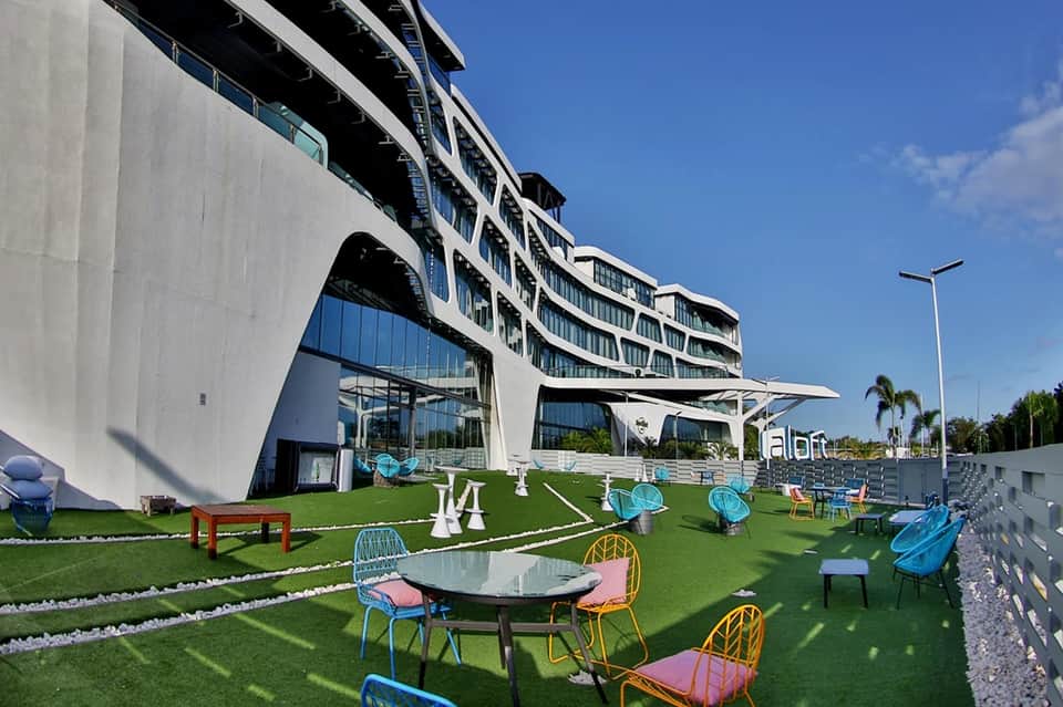 Modern curved hotel building with artificial lawn, colorful seating, and contemporary design