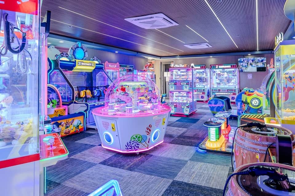 Neon-lit arcade room with colorful gaming machines and entertainment equipment