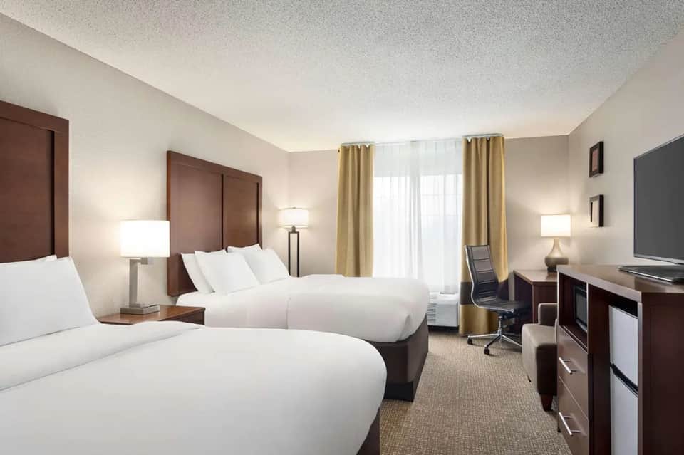 Hotel guest room with two queen beds, neutral tones, and modern furnishings