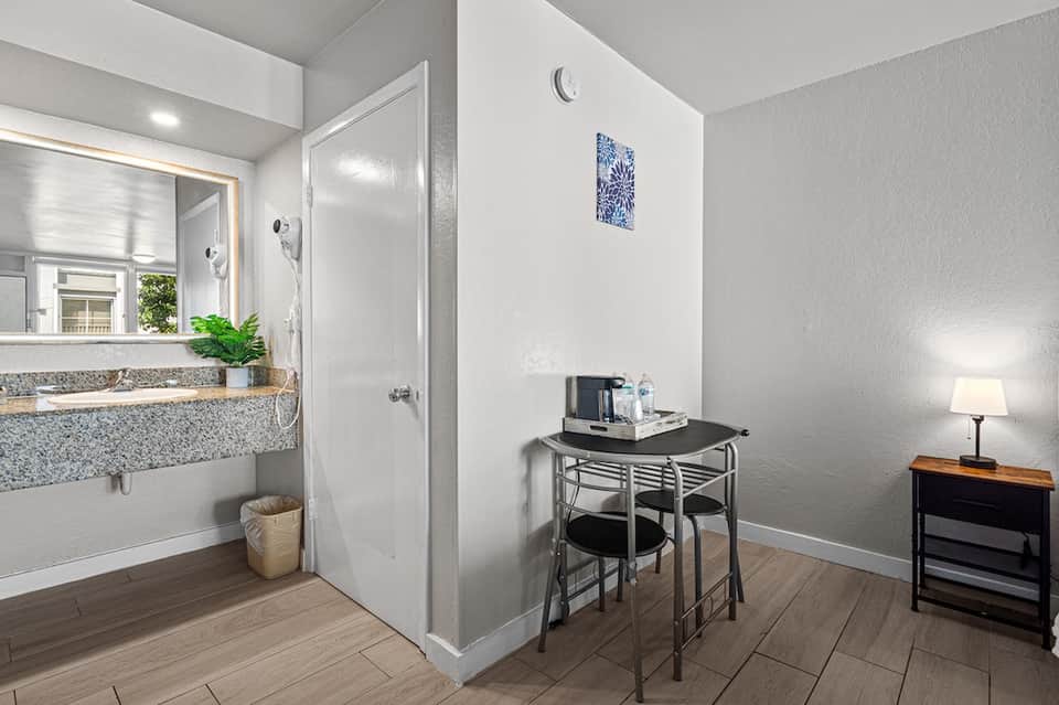 Hotel guest room bathroom with sink, shower, desk area, and hardwood flooring