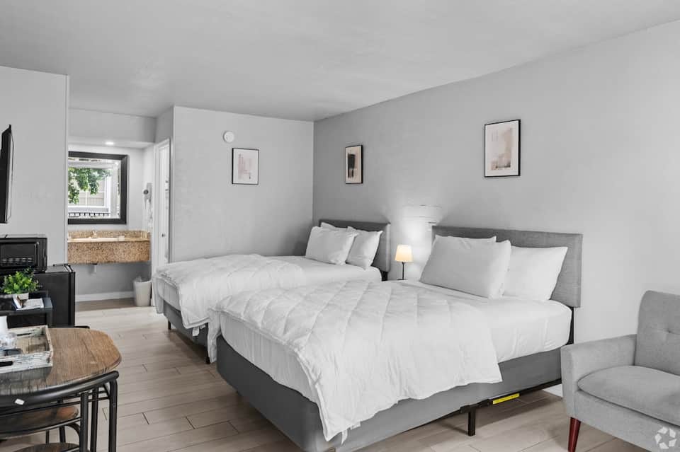 Contemporary hotel room with two queen beds, fireplace, and ensuite bathroom