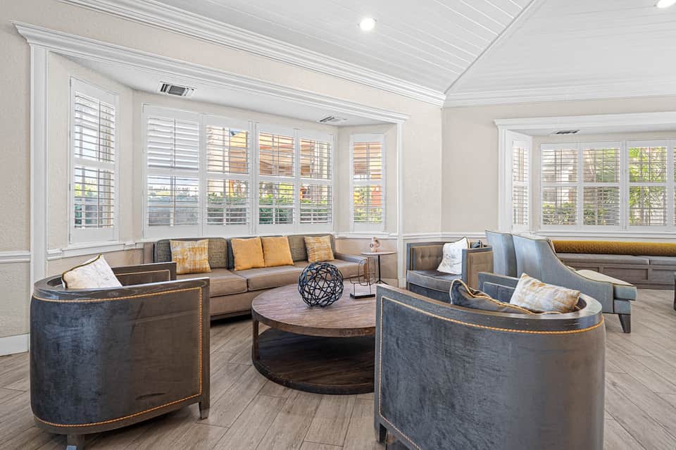 Elegant lounge with built-in seating, shuttered windows, wooden table, and neutral décor