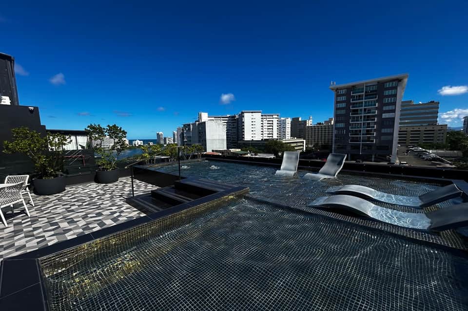 Urban rooftop deck with modern lounge chairs, pool, and city skyline views