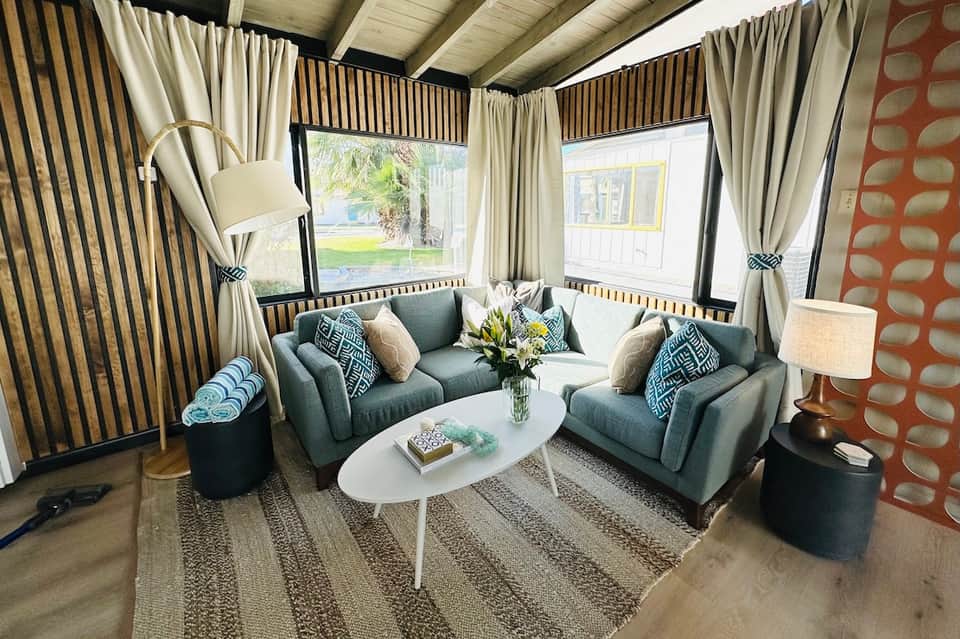Contemporary lounge with gray upholstered chairs, patterned curtains, and ocean view through windows