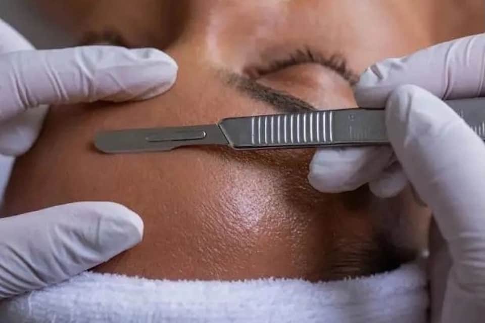 Close-up of microblading procedure with technician using precision tool on client eyebrows