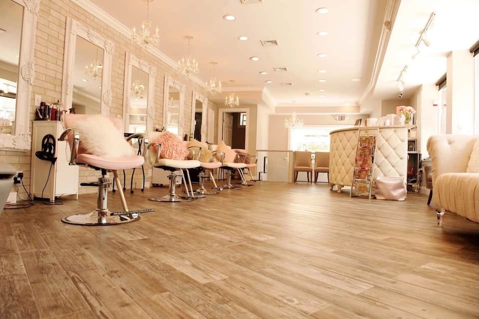 Upscale salon interior with pink chairs, chandeliers, and mirrors lining the walls