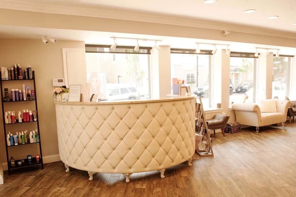 Spa reception area with cream quilted desk, product displays, and lounge seating