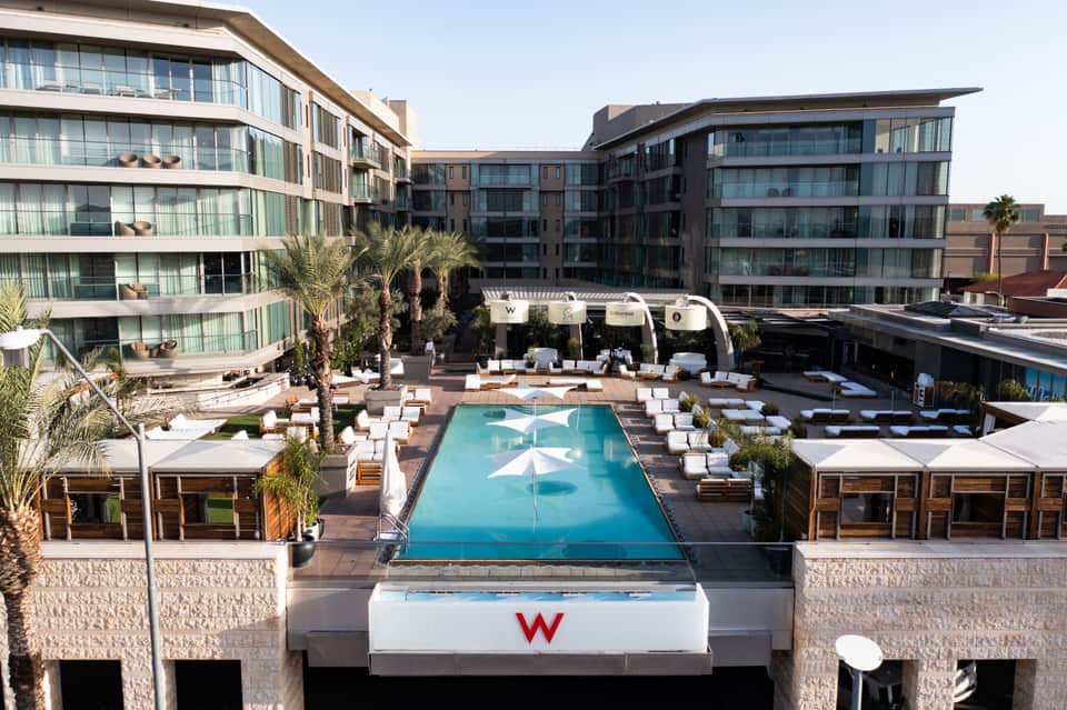 Contemporary hotel pool courtyard with turquoise lap pool, white loungers, and surrounding residences