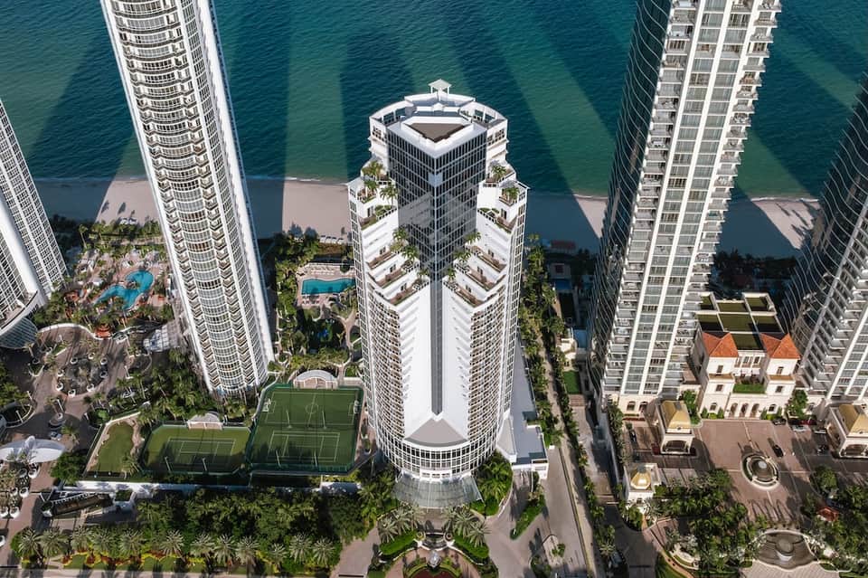 Beachfront residential towers with rooftop amenities and turquoise ocean views from above