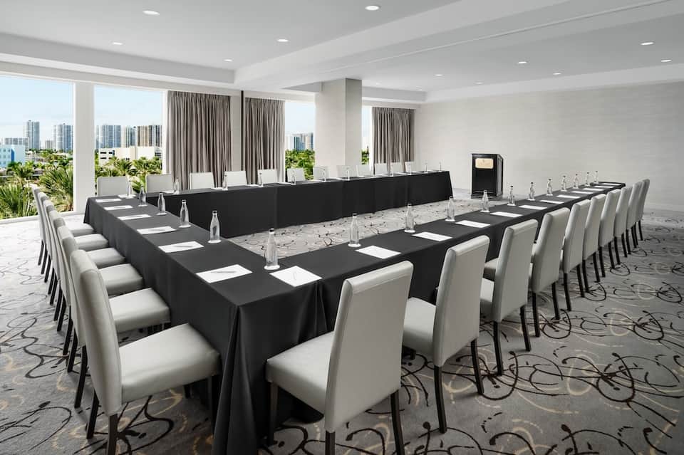 Conference room with long black tables, white chairs, and city views