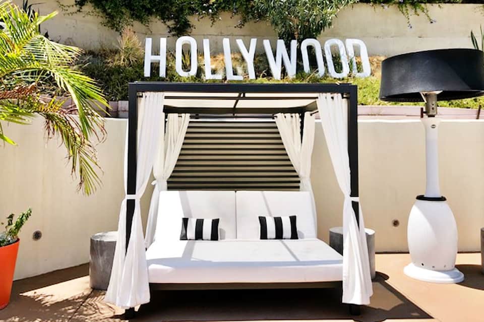 Hollywood-themed bed canopy with white curtains and HOLLYWOOD sign on a rooftop terrace