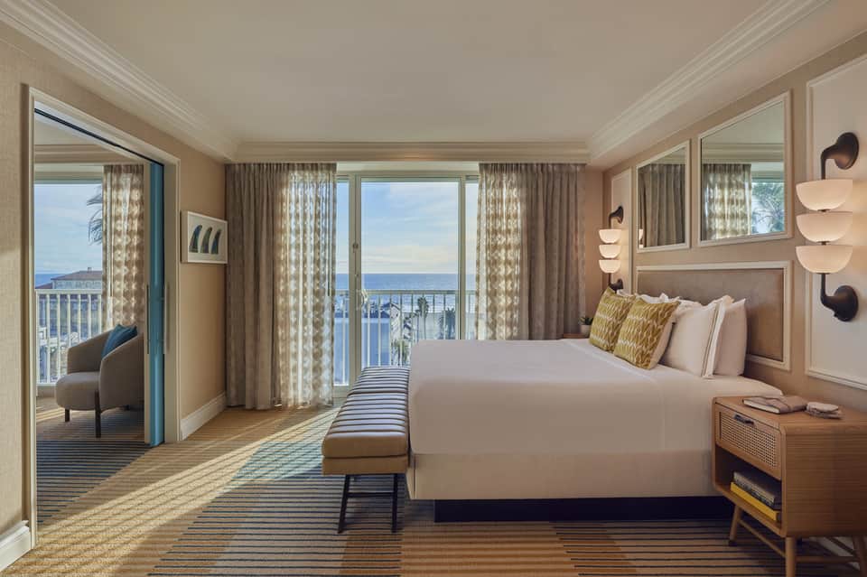 Luxury oceanview bedroom with king bed, balcony, neutral tones, and coastal décor