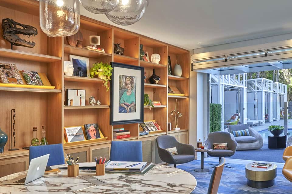 Modern hotel interior with wooden shelving, desk, pendant lights, and patio access